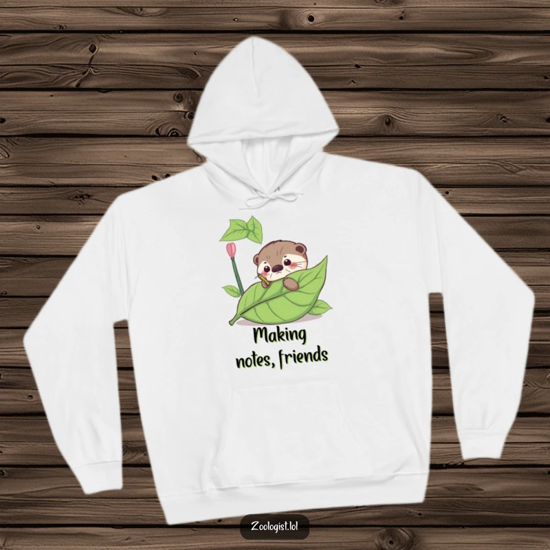Funny hoodie depicting a curious otter meticulously annotating a giant leaf, great for cozy study sessions.